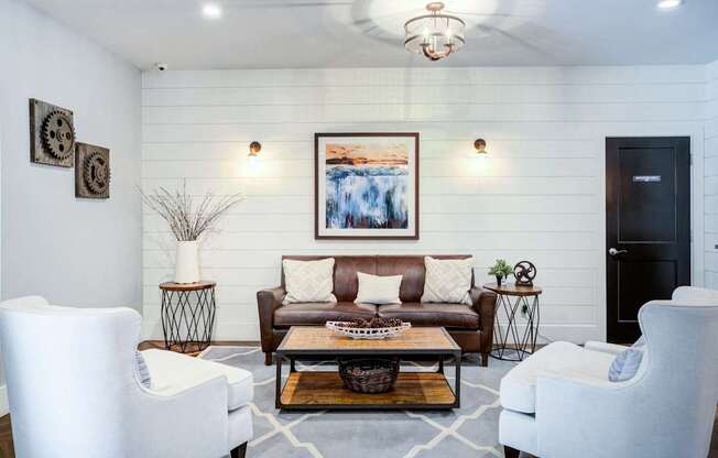 A living room with a white sofa, two white chairs, and a coffee table.