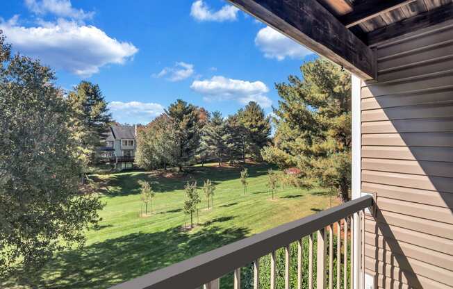 the view from the balcony of a house overlooking a yard and trees