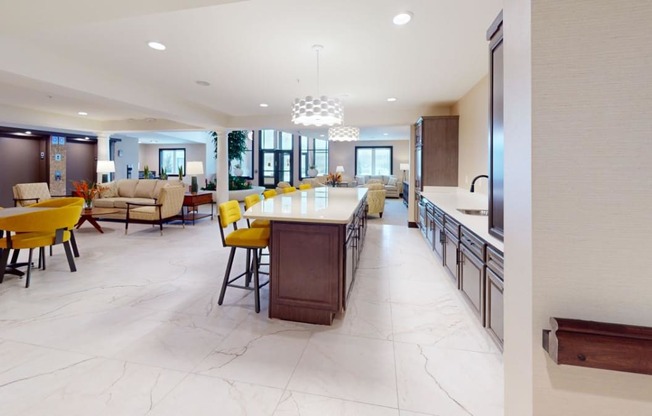a large kitchen with a long bar and yellow chairs