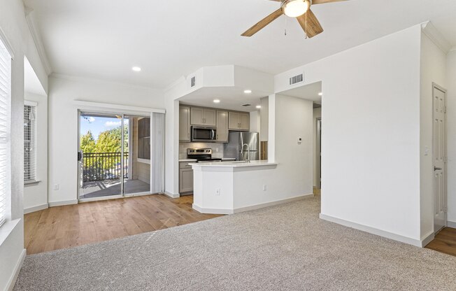 an empty living room with a kitchen and a ceiling fan at The Legends at Eagle Mountain Lake, Fort Worth