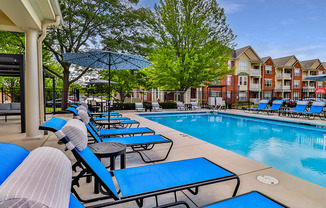 A pool area with sun loungers and a building in the background.