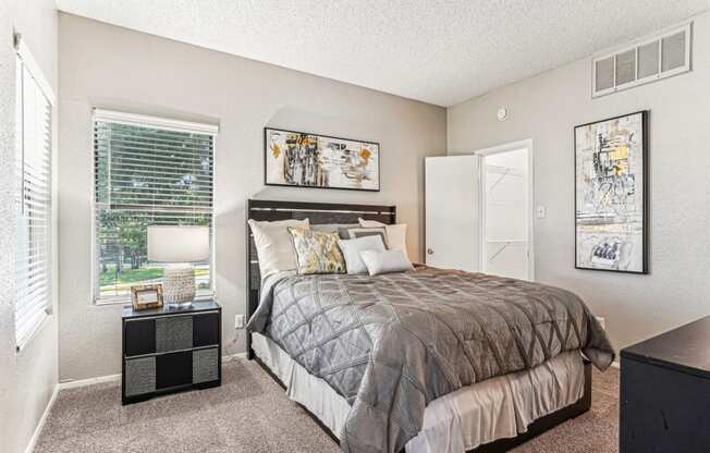 Comfortable bedroom with a grey upholstered bed and neutral decor at Laurels of Sendera apartments in Arlington, TX