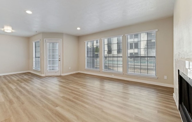 an empty living room with a fireplace and large windows