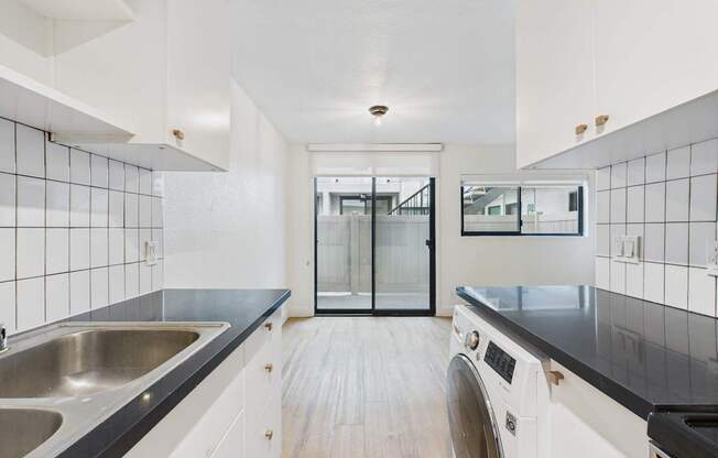 A modern kitchen with a black countertop and white cabinets.