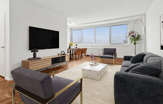 A living room with a grey couch, a wooden entertainment center, and a flat screen TV.