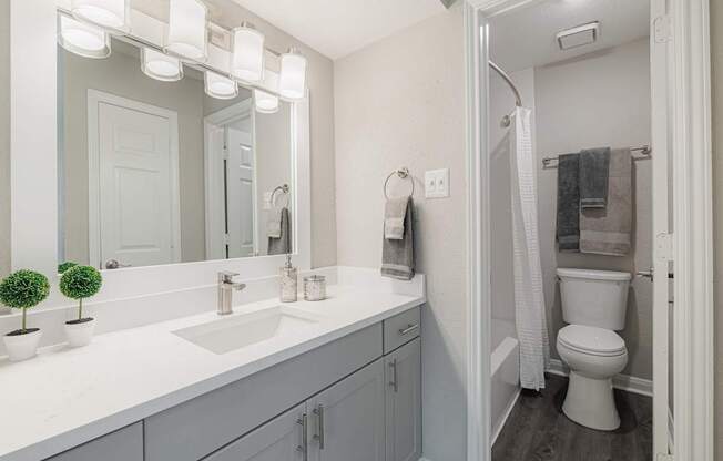 A bathroom with a white counter top and a white toilet.