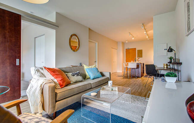 A living room with a couch, a coffee table, and a mirror on the wall.