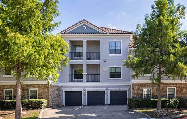 A two-story apartment building with a garage door and balcony.