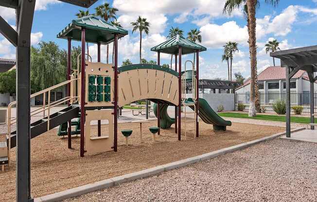 A playground with a green slide and a brown and tan play structure.