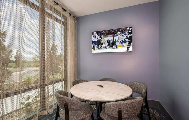 a dining room with a table and chairs and a tv on the wall