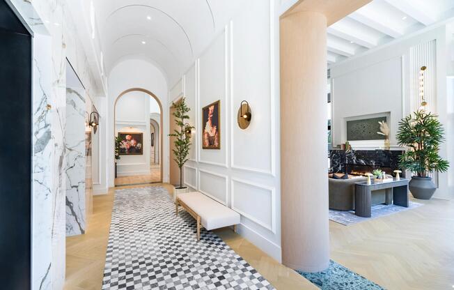 Light-filled community corridor with arched passages, curated artwork, and refined finishes creating an inviting transition between shared living spaces.