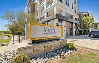 A sign for Axis Apartments in front of a building.