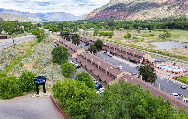 an aerial view of a building with a parking lot and mountains in the background