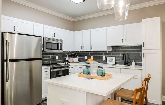 A kitchen with white cabinets and a stainless steel refrigerator.