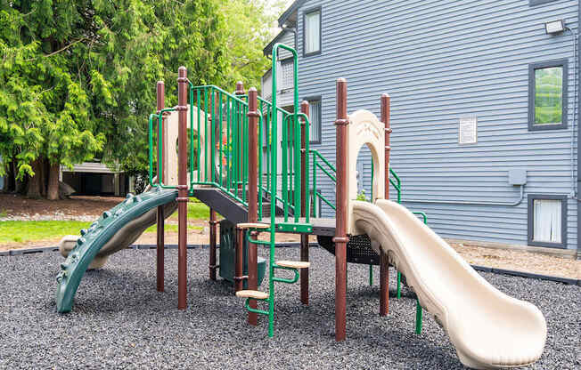 A playground with a green slide and a brown slide.
