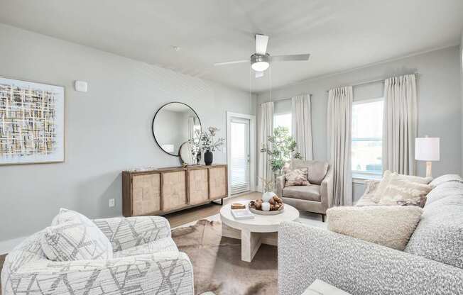 A living room with a white couch, a wooden cabinet, and a painting on the wall at The Ashton at East Park Apartments, Kennesaw, 30144