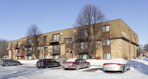 a brick apartment building with cars parked in the snow