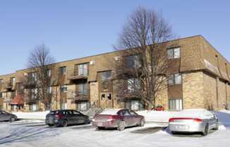 a brick apartment building with cars parked in the snow