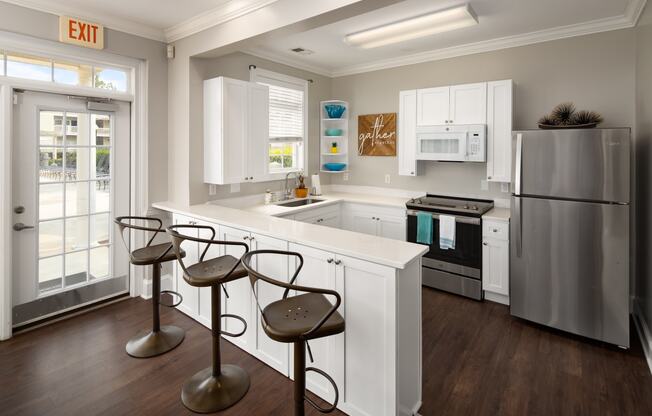 a kitchen with white cabinetry and a white counter top with three stools in front of