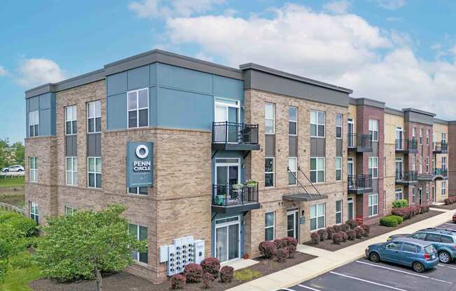 A white car is parked in front of a brick apartment building.