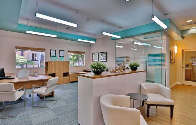 A modern office space with a desk, chairs, and a glass wall.