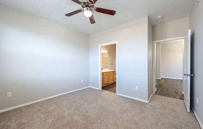 A room with a ceiling fan and carpeted floor.