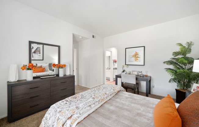 a bedroom with white walls and a large bed with orange pillows