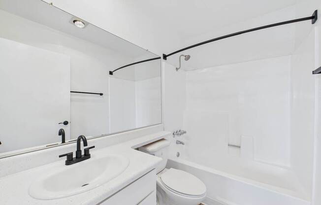 A white bathroom with a sink, toilet, and bathtub.