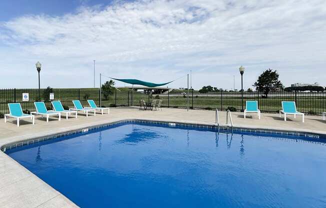 A swimming pool with blue water and white lounge chairs.