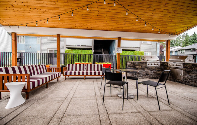 A patio with a striped couch and a table with chairs.