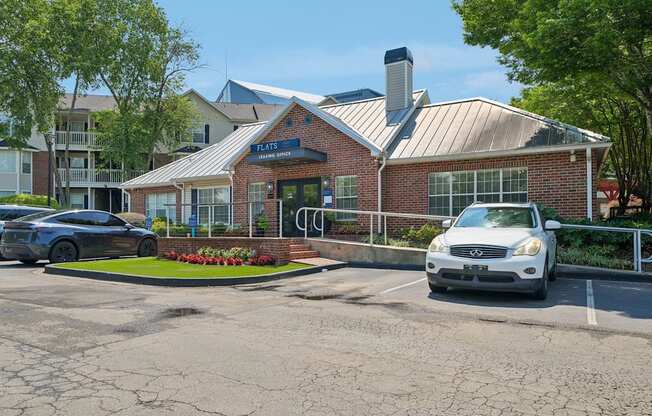 A brick building with a sign that says "FLAIRS" in front of a parking lot.