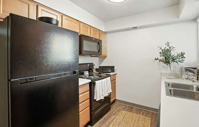 A kitchen with a black refrigerator, microwave, and stove.