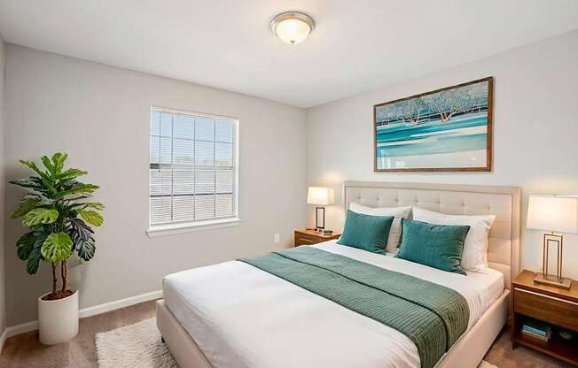 A bedroom with a large bed and a potted plant.