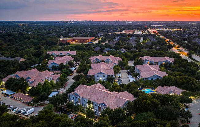 A sunset view of a residential area with houses and parked cars.