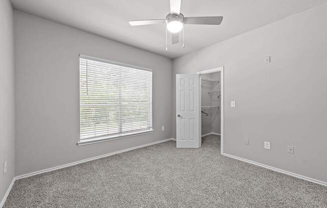 A room with a ceiling fan and a window with blinds.