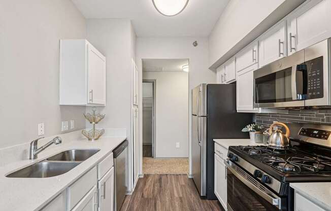 A kitchen with a black refrigerator and stove top oven.