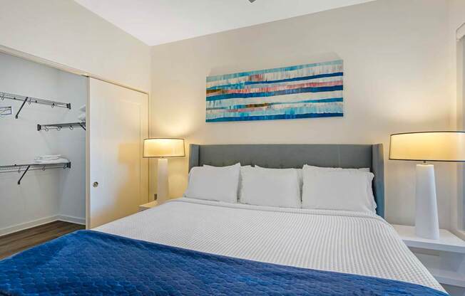 A bedroom with a large bed and a painting on the wall.