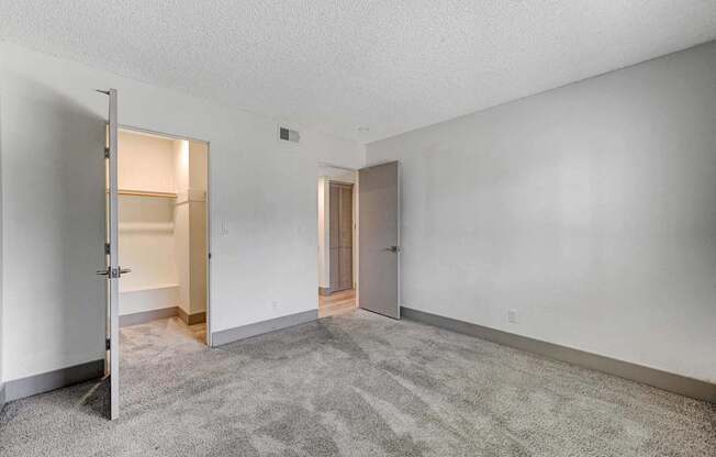 A room with a grey carpet and two doors.
