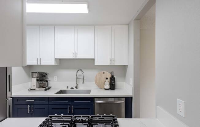 a kitchen with white cabinets and a stove and a sink