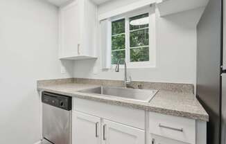A kitchen with white cabinets and a granite countertop.