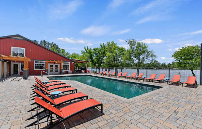 A pool area with red sun loungers and a red building.