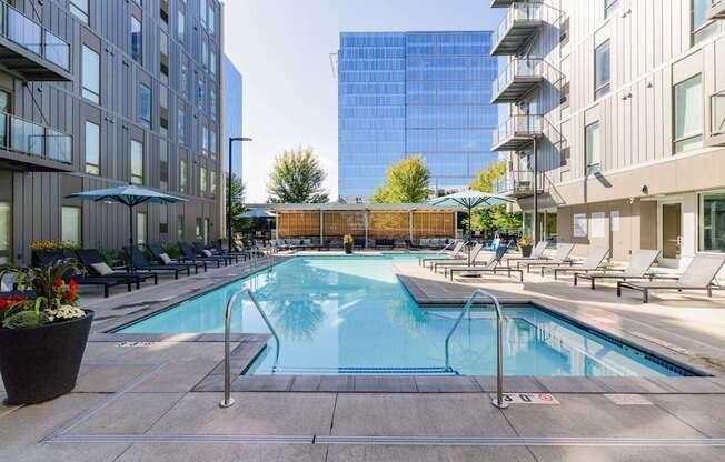 A pool surrounded by chairs and buildings.