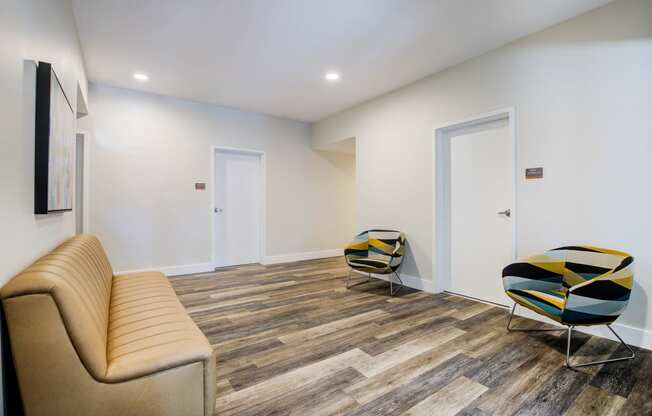 Lobby with Tan Sofa, Hardwood Inspired Floor, White Walls and Yellow/Dark Blue Chairs