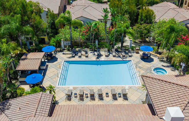 A large swimming pool surrounded by a tiled patio and lounge chairs.