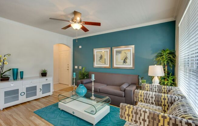 View of Living Room with Ceiling Fan, Entrance, and Plank-Wood Flooring at Raveneaux Apartments