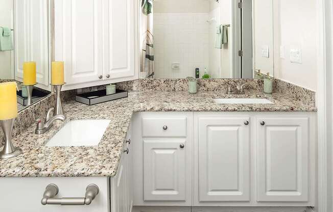 A bathroom with a granite countertop and white cabinets.