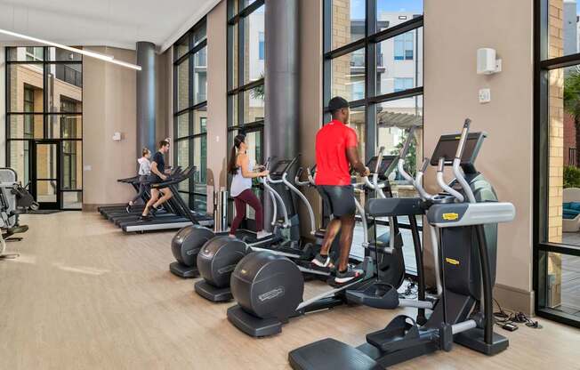 A gym with people working out on treadmilers and elliptical machines.