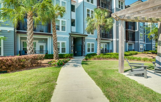 a sidewalk leading to an apartment building with palm trees