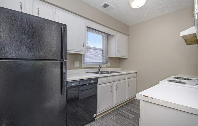 Omaha, NE Maple Ridge Apartments. A kitchen with white cabinets and black appliances