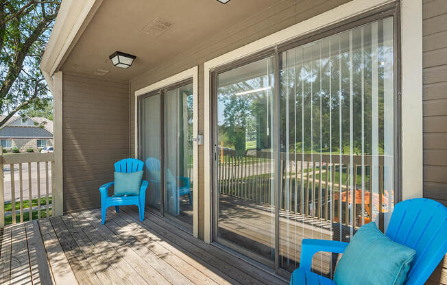 a porch with blue chairs and sliding glass doors